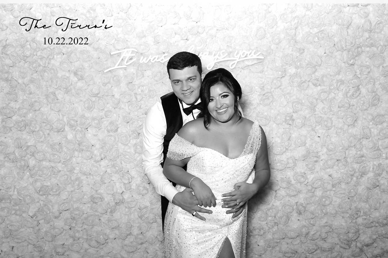 Glam Booth black and white photo of a couple hugging in front of a flower wall